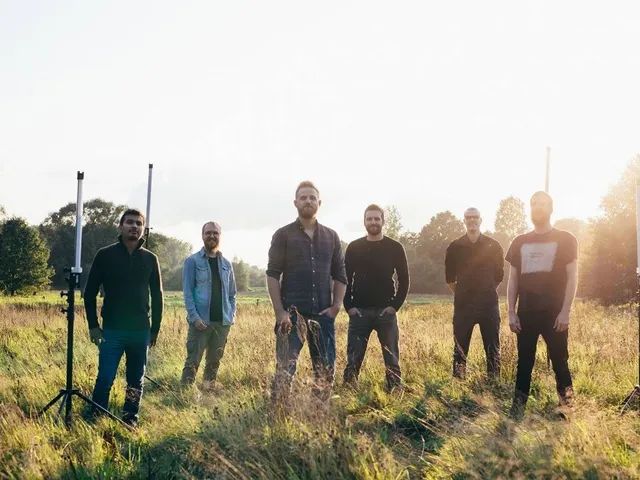 Wanheda (sechs Personen in lässiger Kleidung) stehen auf einer Wiese. Es ist heller Tag.