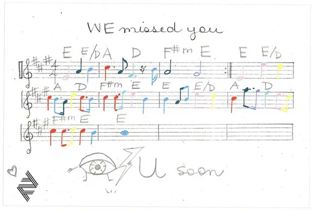 Handschriftliche Notiz, unterschrieben von Arcade Fire mit Noten auf einem Notenblatt und den Worten "We missed you" (Wir haben Euch vermisst). Unter den Noten ist ein gezeichnetes Auge zu sehen, daneben steht "U Soon" für "See you soon" ("Wir sehen uns bald wieder")